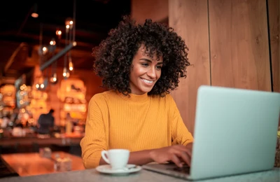 A woman smiling while using her laptop to contact her chiropractor